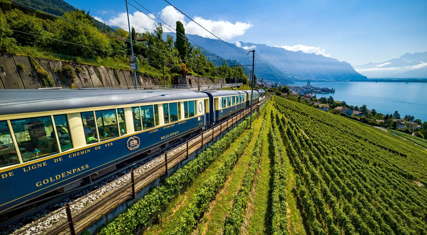 GoldenPass train running beside vineyards and Lake Geneva, a premium scenic journey explained in How the Swiss Travel Pass Works on Trains.