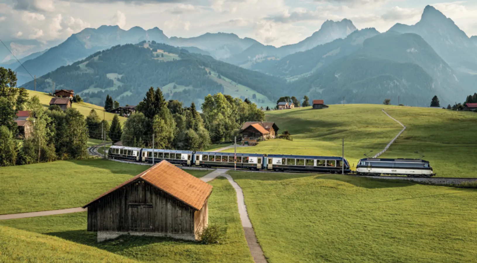 Scenic Swiss train crossing peaceful green countryside on a panoramic route, emphasizing the value of learning Where to Buy Swiss Travel Pass for seamless travel.