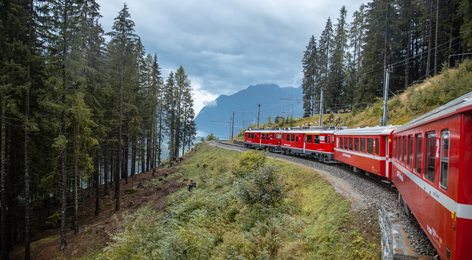 The red Bernina Express train curving across the Brusio circular viaduct, a 360-degree spiral on the UNESCO World Heritage Rhaetian Railway between Switzerland and Italy