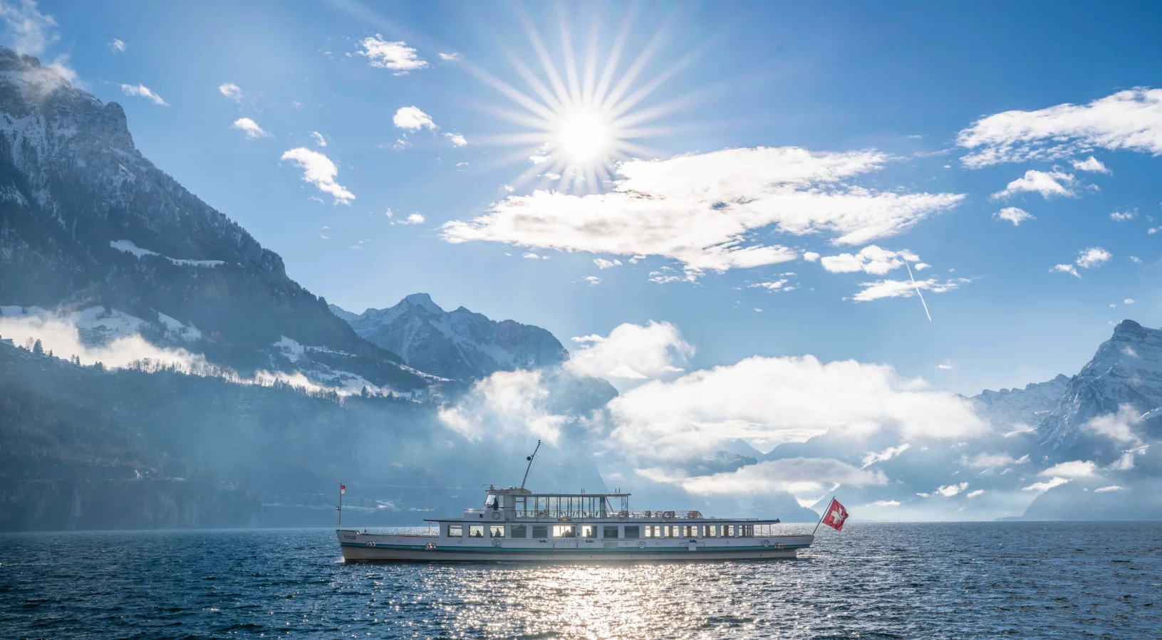 A passenger ship flying the Swiss flag on Lake Lucerne in bright sunshine, illustrating the choice between the Swiss Travel Pass, the Flex pass and the Half Fare Card